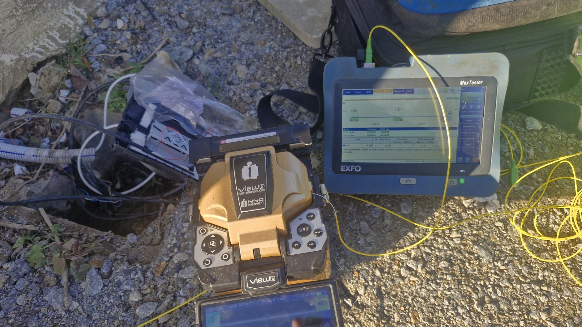 Soudeuse de fibre optique et réflectomètre EXFO en cours de raccordement sur un chantier extérieur.